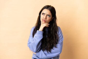 Young caucasian woman over isolated background having doubts while looking up