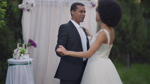 Slow dance of happy couple of newlyweds at wedding altar outdoors. Romantic African American bride and groom dancing first marriage dance in slow motion. Traditions and happiness concept