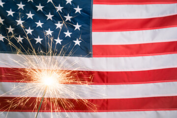 Glowing sparkler against US flag with copy space - obrazy, fototapety, plakaty