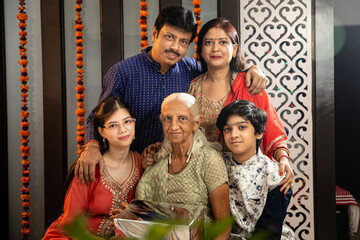 Three generations of an Indian family posing together, parents, grandmother and kids.