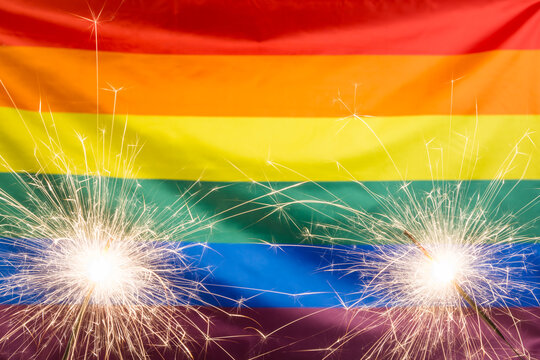 Glowing sparklers against waving rainbow flag with copy space - Powered by Adobe