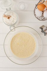 Cooking oatmeal pancakes with bananas. Eggs, buttermilk, sugar, vanilla, oatmeal in a bowl on a white wooden background. Recipe step by step.