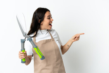 Young caucasian woman holding a plant isolated on white background pointing finger to the side and presenting a product