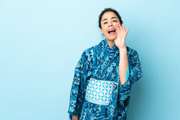 Woman wearing kimono over isolated background shouting with mouth wide open