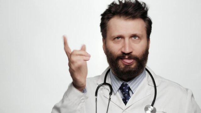 Funny crazy doctor grimaces and grumbles. Male doctor on white background looks at camera and grimaces, makes funny face and grumbles