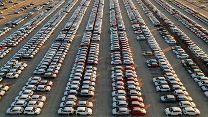 Aerial view new cars lined up in the parking station for import and export business logistic to dealership for sale, Automobile and automotive car parking lot for commercial business industry. © Geza Kurka