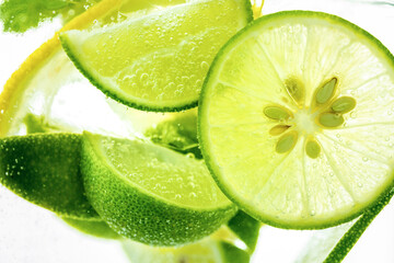 Lemon and line drop in fizzy sparkling water, juice refreshment