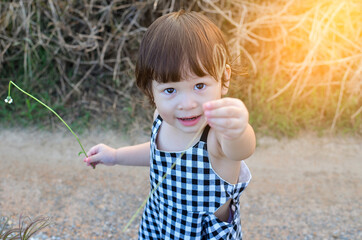 cute little girl is sending flowers in her hand to someone the evening atmosphere with soft sunlight