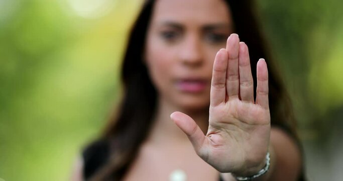 Woman annoyed making stop sign with hand, saying no, expressing defense or restriction