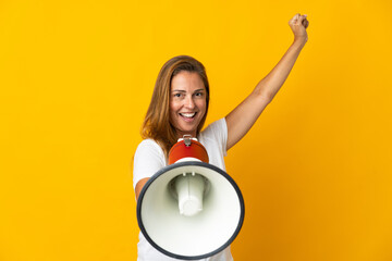 Middle age brazilian woman isolated on yellow background shouting through a megaphone to announce something