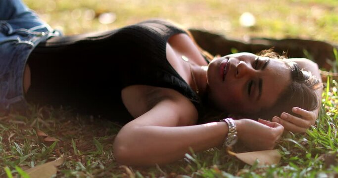 Woman lying on grass outside dreaming. Relaxed tranquil girl lied outdoors