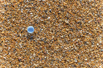 Plastic water bottle cap on the sand at the beach