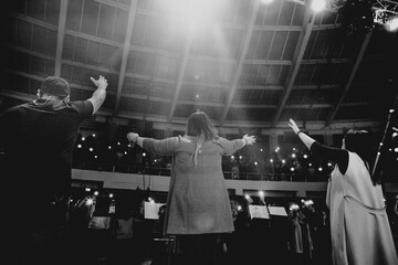 Christians raising their hands in praise and worship at a night music concert - obrazy, fototapety, plakaty