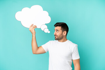 Young handsome caucasian man isolated on blue background holding a thinking speech bubble