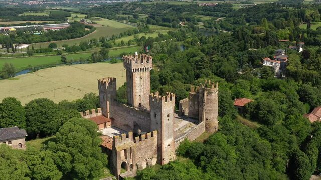 Aerial view of the Italian historic castle Castello Scaligero on a hill, view of the Ponte Visconteo bridge and the Mincio river. Flag of Italy at Scaligero Castle, Verona, Italy.