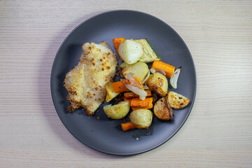 A plate of chicken schnitzel with roasted vegetables.