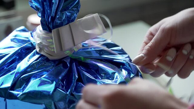 european girl packs a gift in a blue shiny package