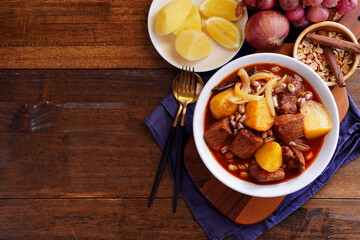 Thai food with rice Pork massaman curry with potatoes, peanuts, coconut milk and onions in a cup on a wooden table