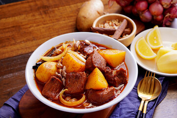 Thai food with rice Pork massaman curry with potatoes, peanuts, coconut milk and onions in a cup on a wooden table