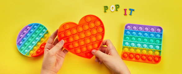 Kid hands playing with colorful pop It fidget toy. Colorful antistress sensory toy fidget push pop it.