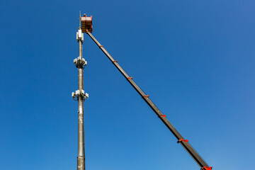Fototapeta premium Engineer is working on thecellular phone repeater mast from An aerial work platform, also known as an aerial device, elevating work platform, cherry picker, bucket truck .