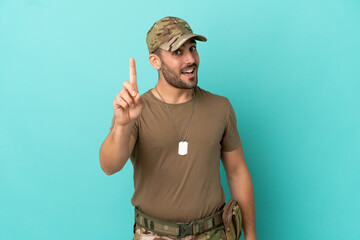 Military with dog tag over isolated on blue background showing and lifting a finger