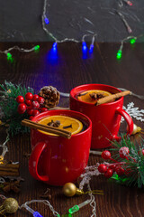 Aromatic, hot and delicious mulled wine with orange, cinnamon, star anise and cloves in red cups...