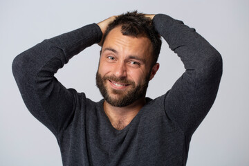 Mature contented man with beard smiling on white background with gray jumper