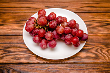 Branch of red grapes lies on a brown wooden background
