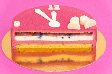 Red cake section with many layers, on pink background. White clock with 9 and 12 hours.