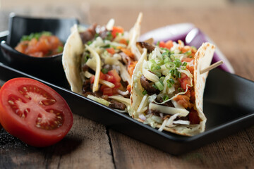 Slow cooked short ribs on tortillas with a spring onion tomato salsa isolated on wooden table