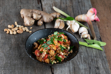 Gai Pad Med Mamuang or Thai Cashew Chicken in black bowl on wooden rustic table