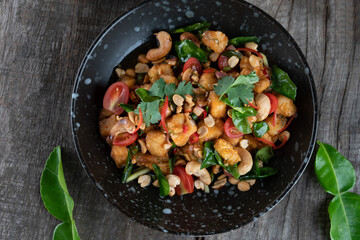 Gai Pad Med Mamuang or Thai Cashew Chicken in black bowl on wooden rustic table
