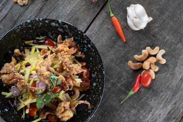 Somtam (Papaya Salad) with pork crackling isolated on rustic wooden table