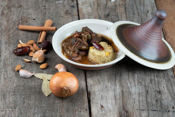 Slow cooked lamb with potato and dates served with warm couscous and chickpeas isolated on the wooden table