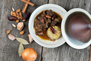Slow cooked lamb with potato and dates served with warm couscous and chickpeas isolated on the wooden table