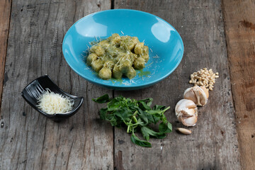 Homemade gnocchi with pesto sauce, parmesan and basil isolated on wooden table