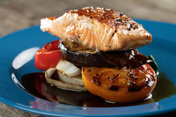 Grilled Salmon steak with vegetables isolated on rustic wooden table