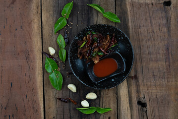 Top view of Moo ded deaw - deep fried dried pork with chilli and sriracha sauce isolated on the wooden table