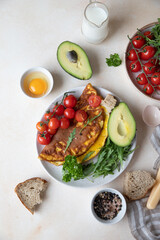 Omelette served with avocado, cherry tomatoes and arugula on ceramic plate. Healthy and tasty keto breakfast or brunch. Ketogenic diet. 
