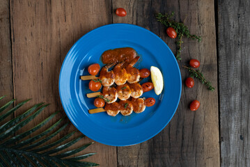 Fototapeta premium Top view of grilled marinated prawns with cherry tomato confit isolated on wooden table
