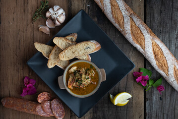 Top view of Gambas Pil Pil - Sizzling prawns with chili and garlic served with bread on the side isolated on wooden rustic table