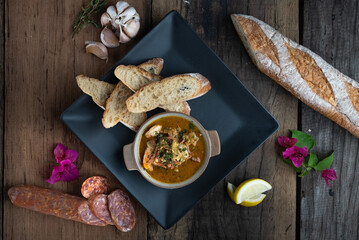 Top view of Gambas Pil Pil - Sizzling prawns with chili and garlic served with bread on the side isolated on wooden rustic table