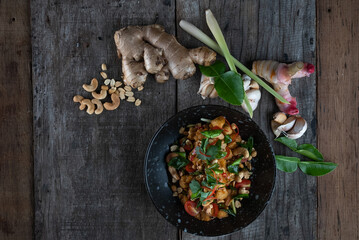 Gai Pad Med Mamuang or Thai Cashew Chicken in black bowl on wooden rustic table