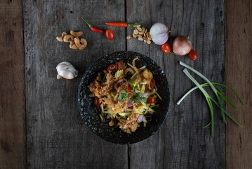 Top view of Somtam (Papaya Salad) with pork crackling isolated on rustic wooden table