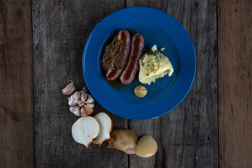 Top view of pork sausages in onion gravy sauce served with mashed potatoes isolated on wooden table