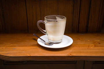 A drunk cup of cappuccino on a wooden table top
