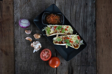 Top view of slow cooked short ribs on tortillas with a spring onion tomato salsa isolated on wooden table