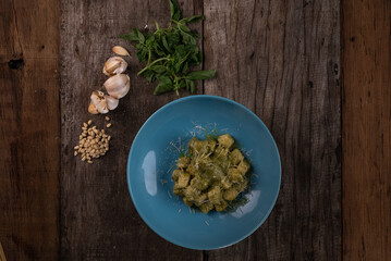 Top view of homemade gnocchi with pesto sauce, parmesan and basil isolated on wooden table