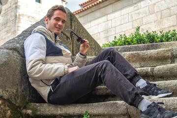 portrait of young man on stairs holding sunglasses